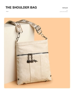 Detail of wide ethnic pattern strap and metal kangaroo zippers on cream shoulder bag