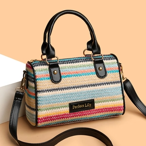 Colorful woven straw beach bucket bag with black leather handles and long shoulder strap