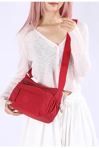 Detailed view of red waterproof nylon crossbody bag with multiple front zipper pockets