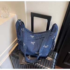 Nahaufnahme der Denim-Tasche mit weißer Schleifenstickerei und gewebtem Reißverschluss