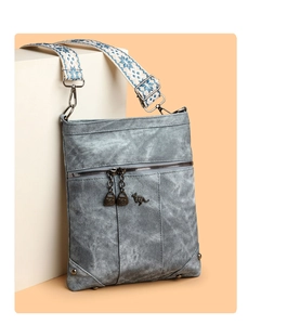 Close-up of a blue-grey crossbody bag with metal kangaroo logo and ethnic patterned straps