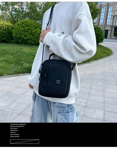 Detail of waterproof black nylon crossbody bag with adjustable strap and metal logo