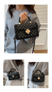 Detail of black leather crossbody bag featuring gold camellia lock and letter monogram print