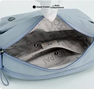 Detailed interior of a light blue nylon bag showing a zippered pocket and large main compartment