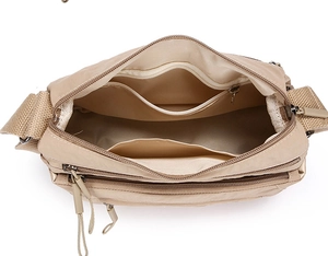 Detail view of large capacity beige oxford cross-body bag with multiple interior pockets