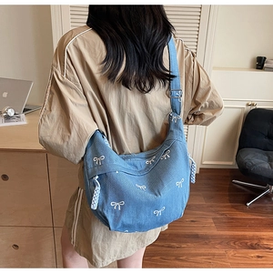 Detail der hellblauen Denim-Hobo-Tasche mit weißen Schleifen und silberner Metallschnalle