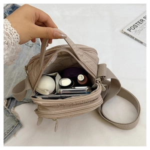 Detailed interior of beige nylon crossbody bag showing spacious compartments and storage