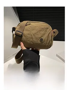 Detail of khaki nylon puff crossbody bag with metal logo and layered storage design
