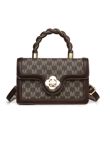 Detail of retro brown square bag with M-pattern print, woven handle and gold floral clasp