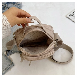 Detail of spacious main compartment and branded lining in this khaki nylon crossbody bag