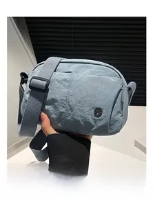 Light grey nylon crossbody puff bag showing fabric texture and round metal logo detail