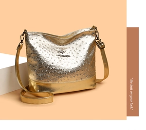 Detail of gold ostrich texture material and metallic kangaroo logo on crossbody bag