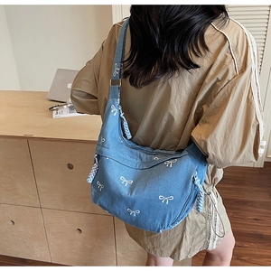 Detail der blauen Denim-Umhängetasche mit weißen Bogenstickereien und Mondform-Design