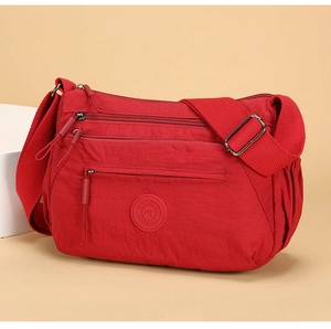 Macro shot of red nylon shoulder bag featuring multiple front zipper pockets for storage