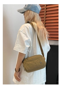 Detail of olive green puffy crossbody bag with adjustable strap and metal logo