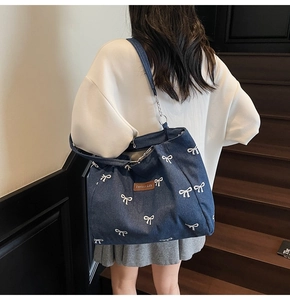 Detail of blue denim tote bag with white bow patterns and brown leather patch