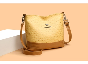 Detail of kangaroo logo on yellow and brown ostrich texture boston crossbody bag