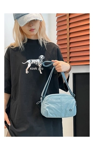 Detail of light blue crossbody puff bag with pleated texture and adjustable strap