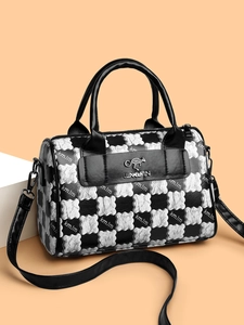 Close-up of black and white checkered Boston bag with silver metal logo and leather handles