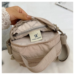Detail of the multi-layer interior and branded lining of this beige nylon crossbody bag