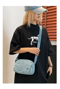 Detail view of the light blue quilted crossbody bag featuring a functional front pocket