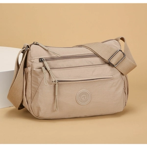 Detail view of beige nylon multi-layer messenger bag with three zip pockets and wide strap