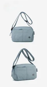 Front and side angle view of light blue lightweight crossbody bag with logo detail