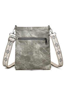Detail view of washed canvas crossbody bag with vintage texture and patterned strap