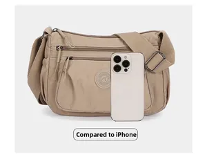 Beige nylon crossbody bag size comparison with smartphone showing multiple zipper pockets