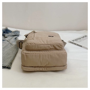 Detail view of khaki waterproof nylon crossbody bag with three zipper compartments