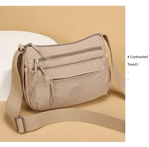 Macro side view of a beige Oxford nylon crossbody bag with multi-layer zipper compartments