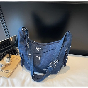 Nahaufnahme der blauen Jeans-Schultertasche mit weißen Schleifen und Kordelverzierung