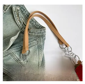 Detail of red and white striped woven tote with brown leather handles and metal chain