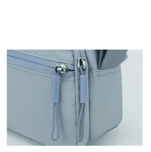 Detailed close-up of brand hardware and textured nylon fabric on crossbody puff bag
