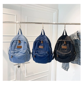 Detailed comparison of light blue, dark blue, and black washed denim backpacks on hangers