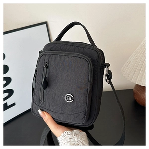Macro detail of waterproof black nylon crossbody bag with multi-zipper pockets and metal logo