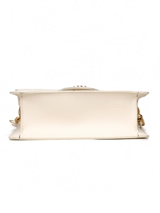 Close-up of cream white leather bag bottom showing stitching and gold chain hooks