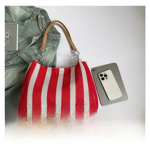 Detail of red and white striped tote bag with leather handles and metallic chain