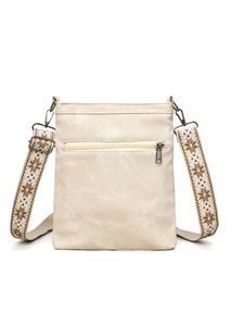 Detail of cream canvas crossbody bag featuring wide woven strap and metal zipper