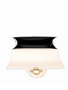 Detail view of the cream crossbody bag interior with flower clasp and black lining