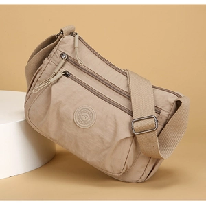Detail view of khaki nylon crossbody bag with multi-layer zippers and adjustable strap