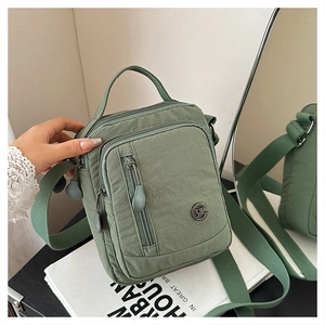 Detail of green nylon crossbody bag with adjustable strap and multiple zipper pockets