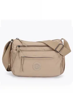 Detail view of khaki nylon crossbody bag showing multiple zipper pockets and fabric strap