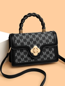 Detail of black crossbody bag featuring M-pattern monogram and gold floral clasp