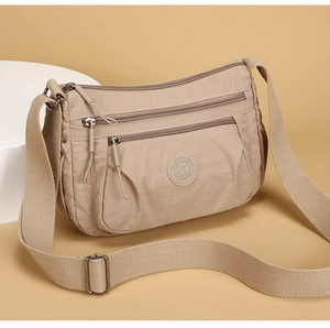 Side view of beige nylon crossbody bag featuring a triple-zipper design and adjustable strap