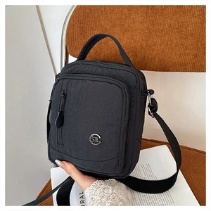 Close-up of waterproof nylon shoulder bag with multiple zipper compartments and handle