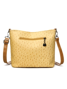 Close-up of yellow ostrich pattern leather handbag featuring a back zipper pocket and strap