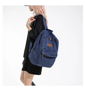 Deep blue denim backpack featuring vintage style and brown leather logo patch detail