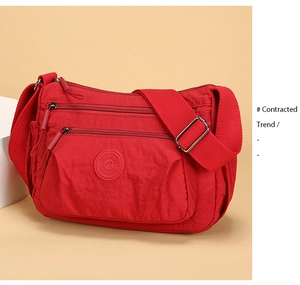 Macro shot of red nylon crossbody bag showing multiple zip pockets and wide strap
