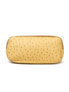 Detailed view of yellow ostrich embossed leather texture with brown edge trim on boston bag